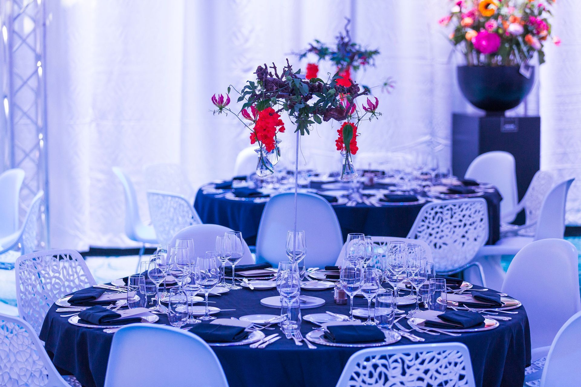 Elegant banquet tables set with floral centerpieces, white chairs, and dark blue tablecloths.