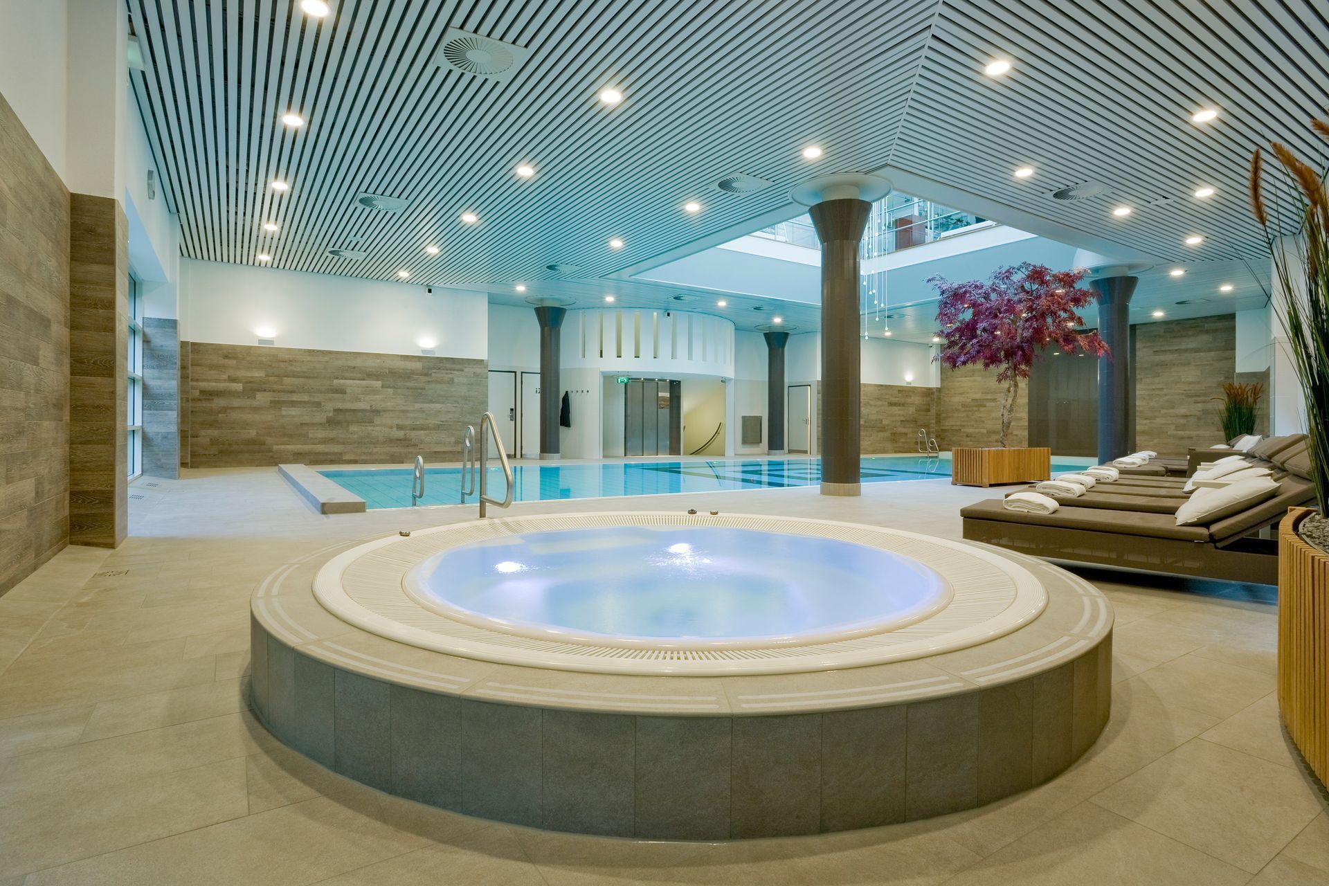 Indoor spa with a hot tub, swimming pool, seating area, and decorative ceiling.
