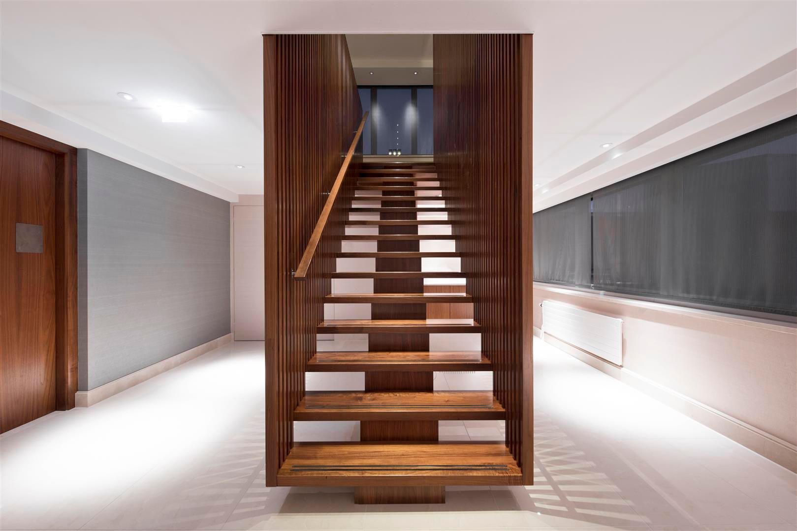 Wooden staircase with white risers, framed by wood panels, in a modern hallway with light walls.