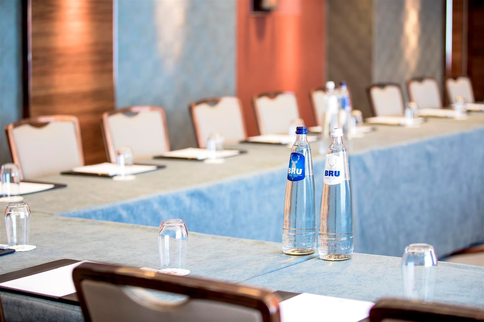 Conference table set for a meeting, with water bottles and individual place settings.