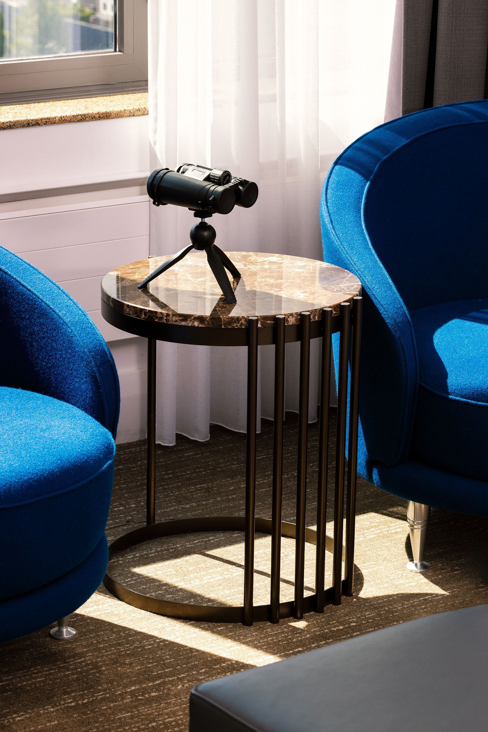 Blue chairs flank a small table with binoculars on a tripod.