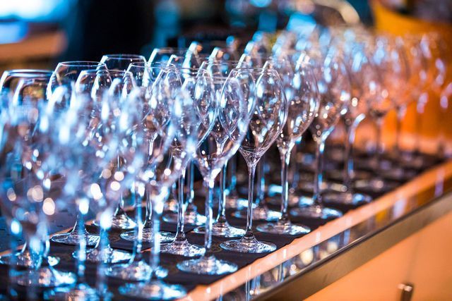 Row of clean, empty wine glasses on a counter, with a blurred background.