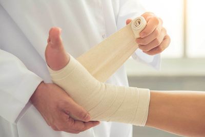 Ankle Sprains — Doctor Bandaging Woman's Ankle in Jackson, MI