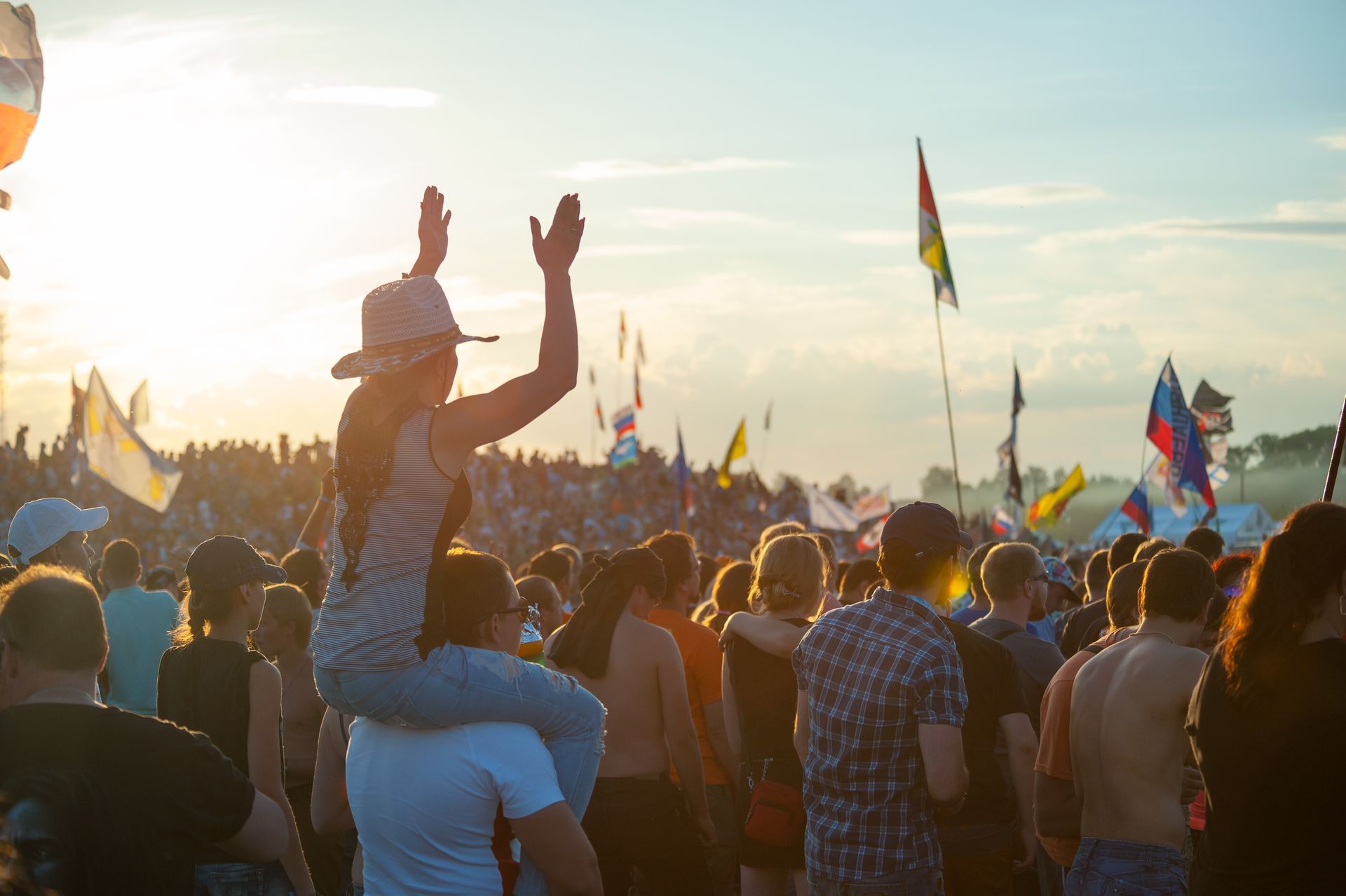 A woman is sitting on a man 's shoulders at a music festival.