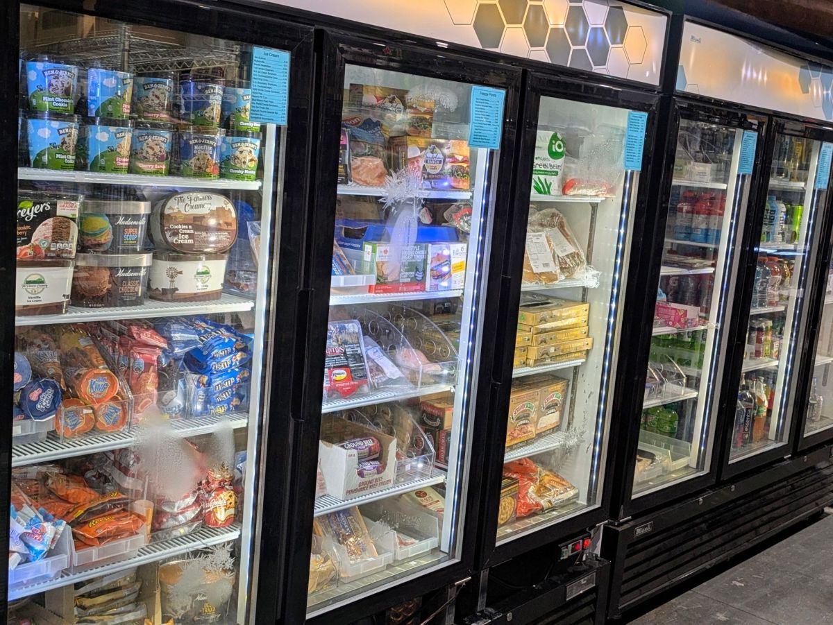 A row of refrigerators filled with lots of food in a grocery store.