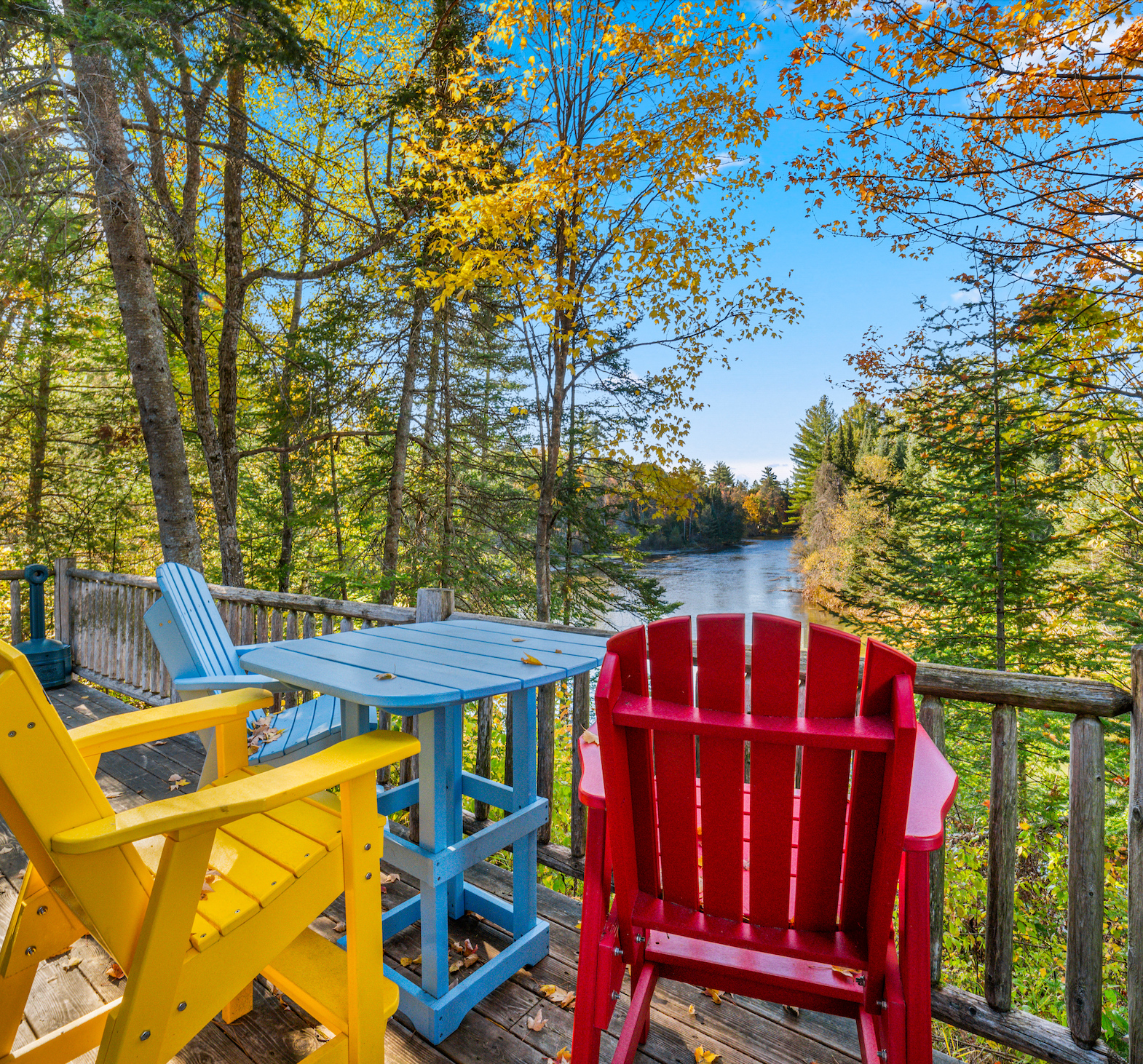 A deck with a table and chairs overlooking a lake.