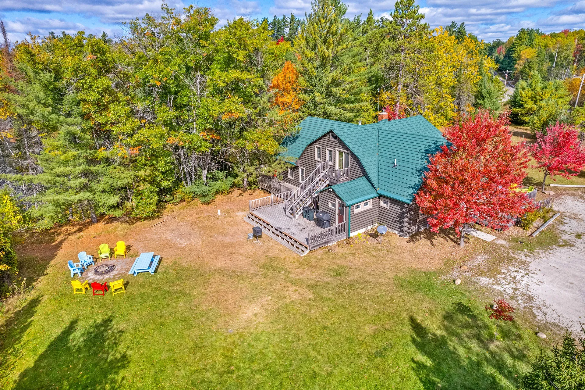 An aerial view of a log cabin surrounded by trees and a fire pit.