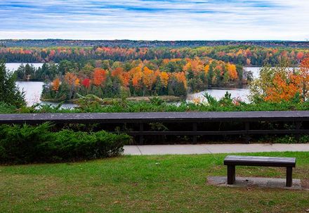 There is a bench in the foreground and a view of a lake in the background.