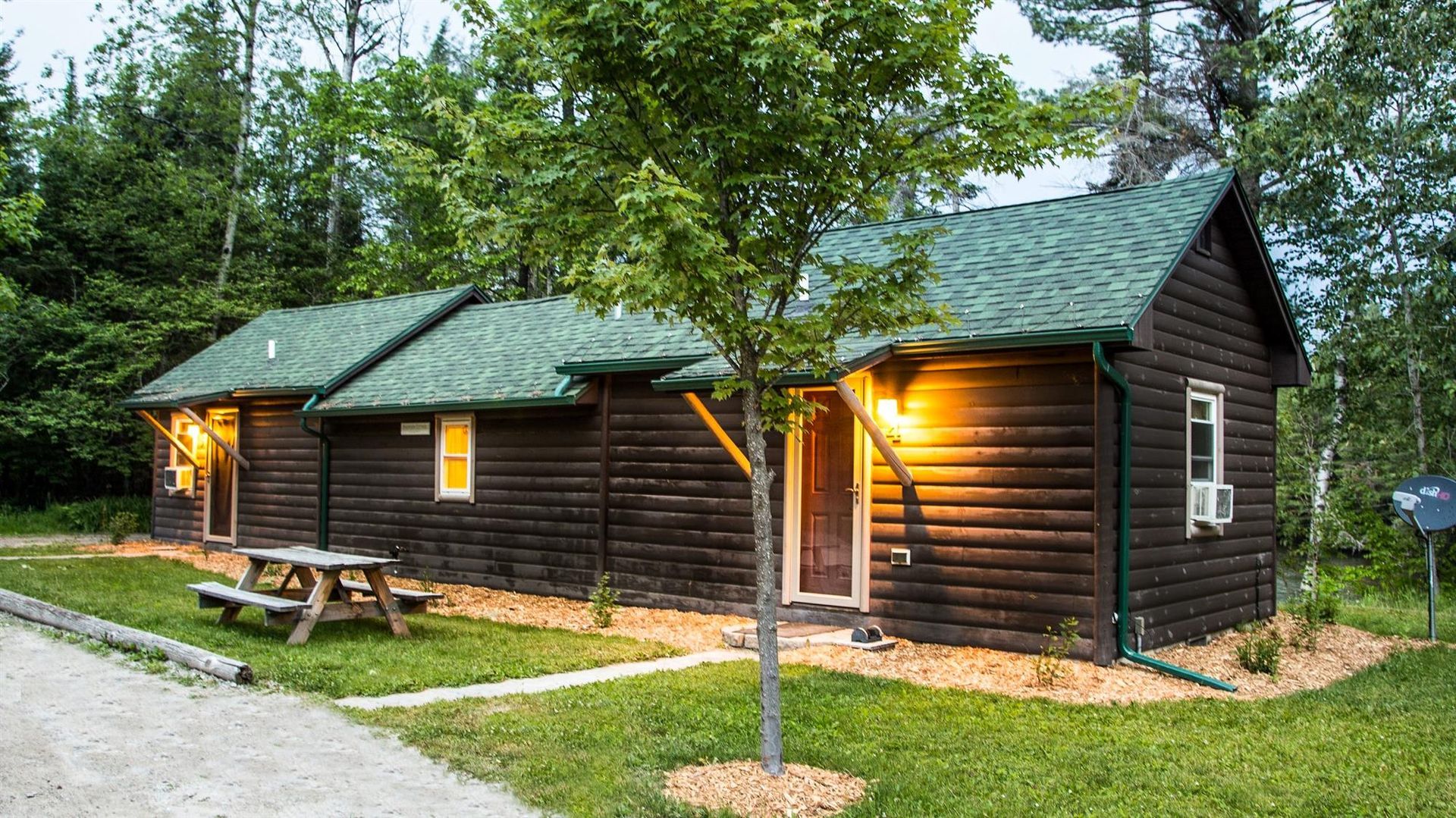 A couple of log cabins with a picnic table in front of them.