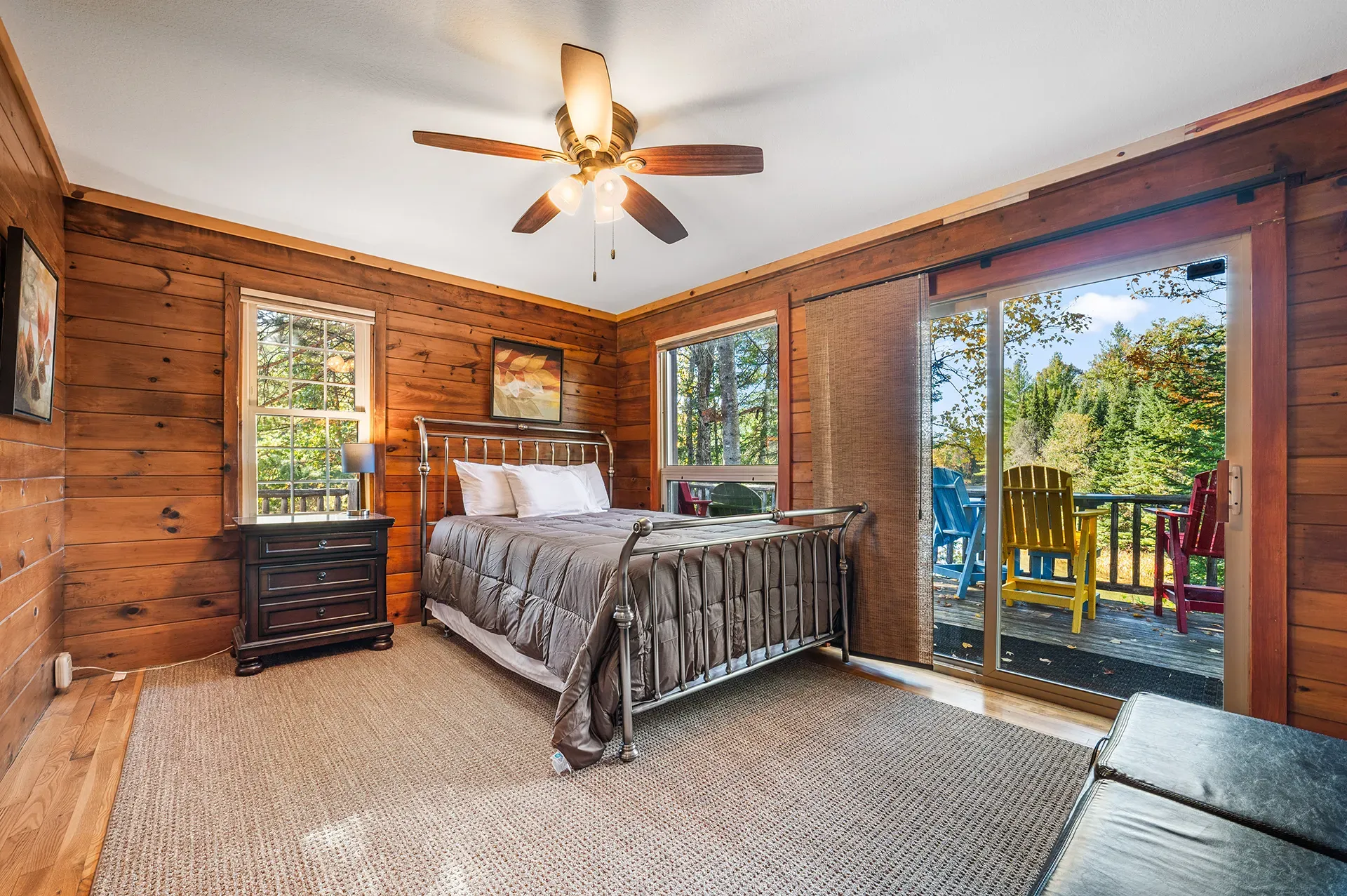 A bedroom with a bed , nightstand , ceiling fan and sliding glass doors.