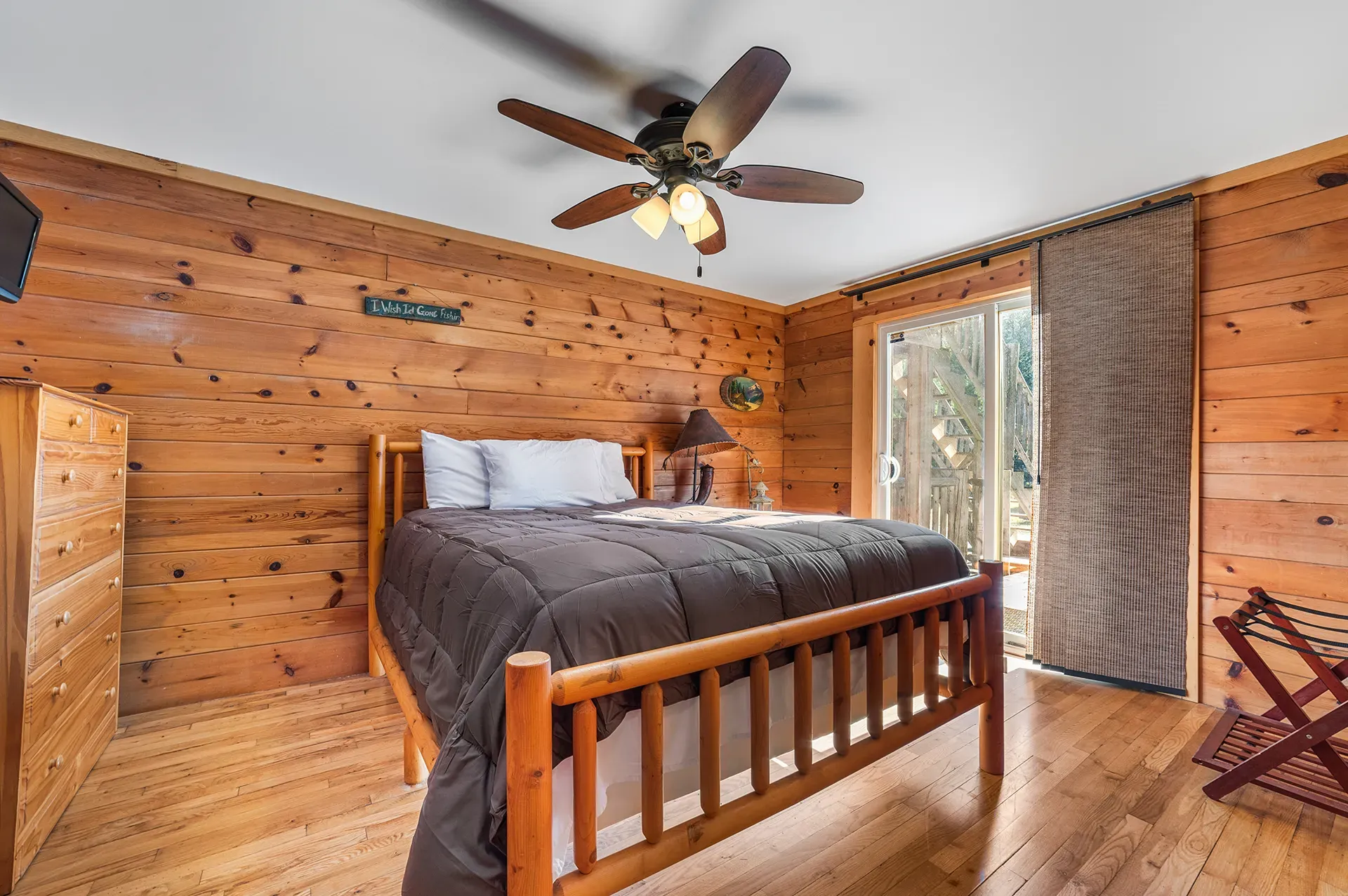 A bedroom in a log cabin with a king size bed and a ceiling fan.