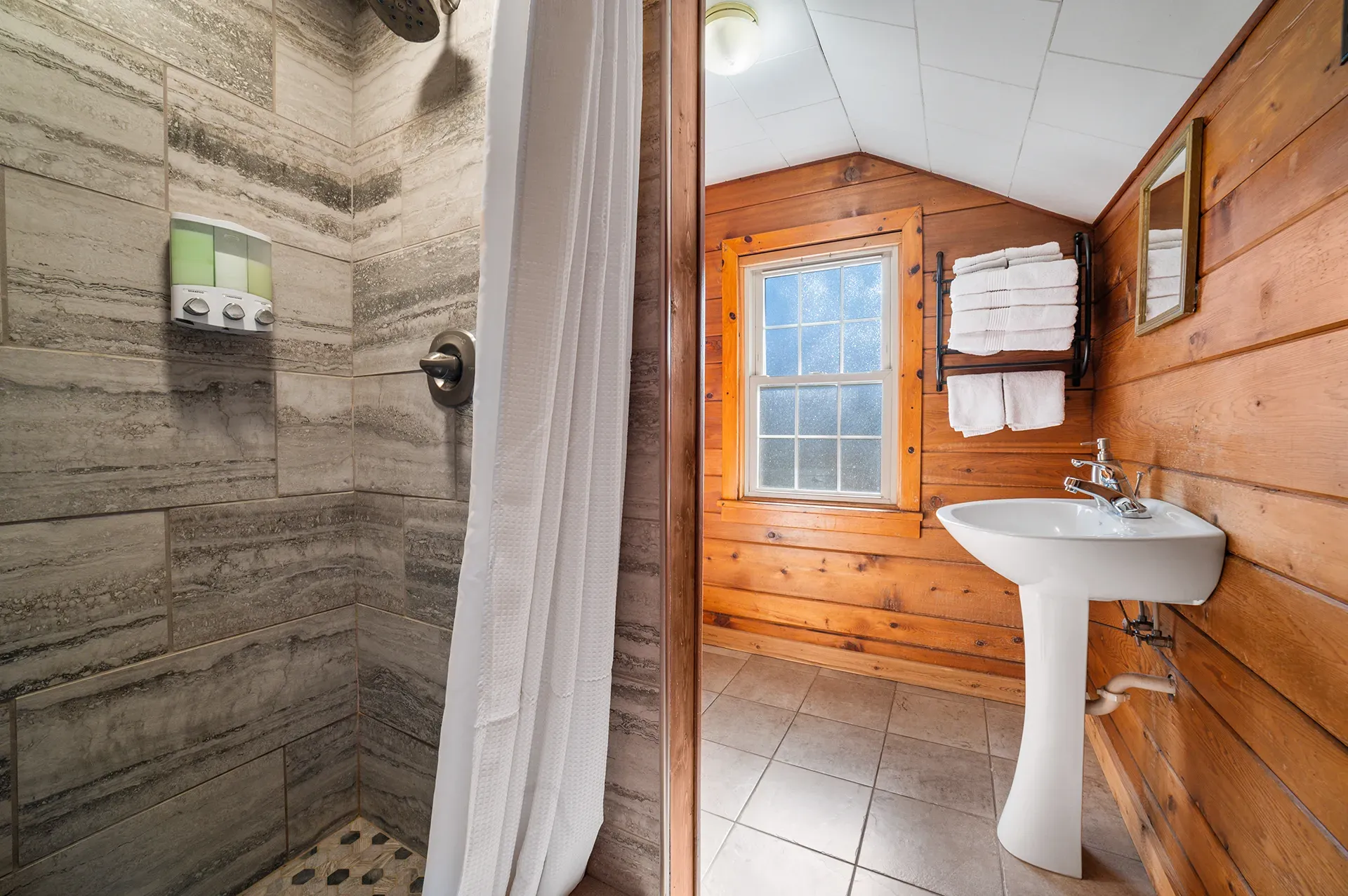 A bathroom with a sink , shower and window.