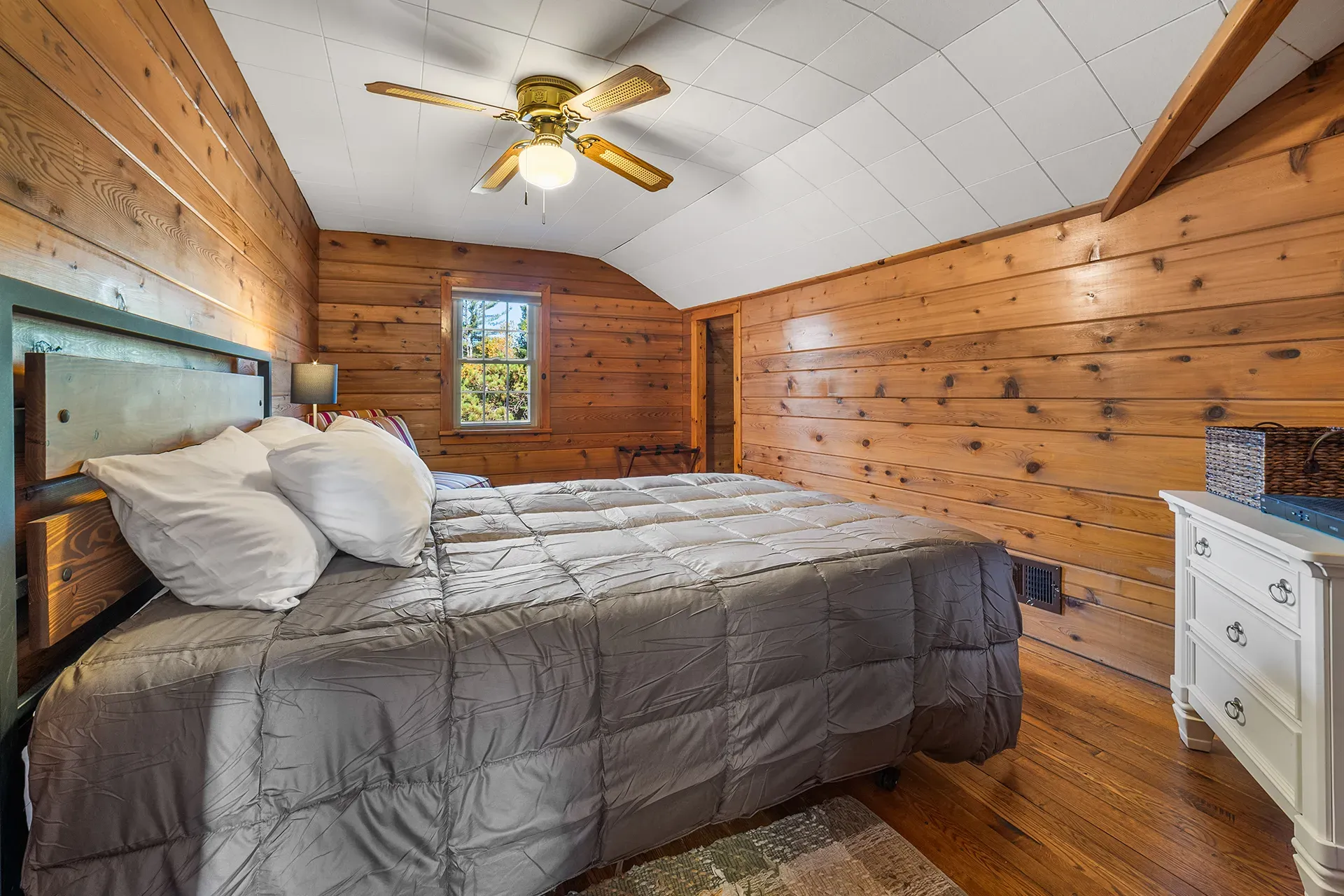 A bedroom in a log cabin with a king size bed and a ceiling fan.