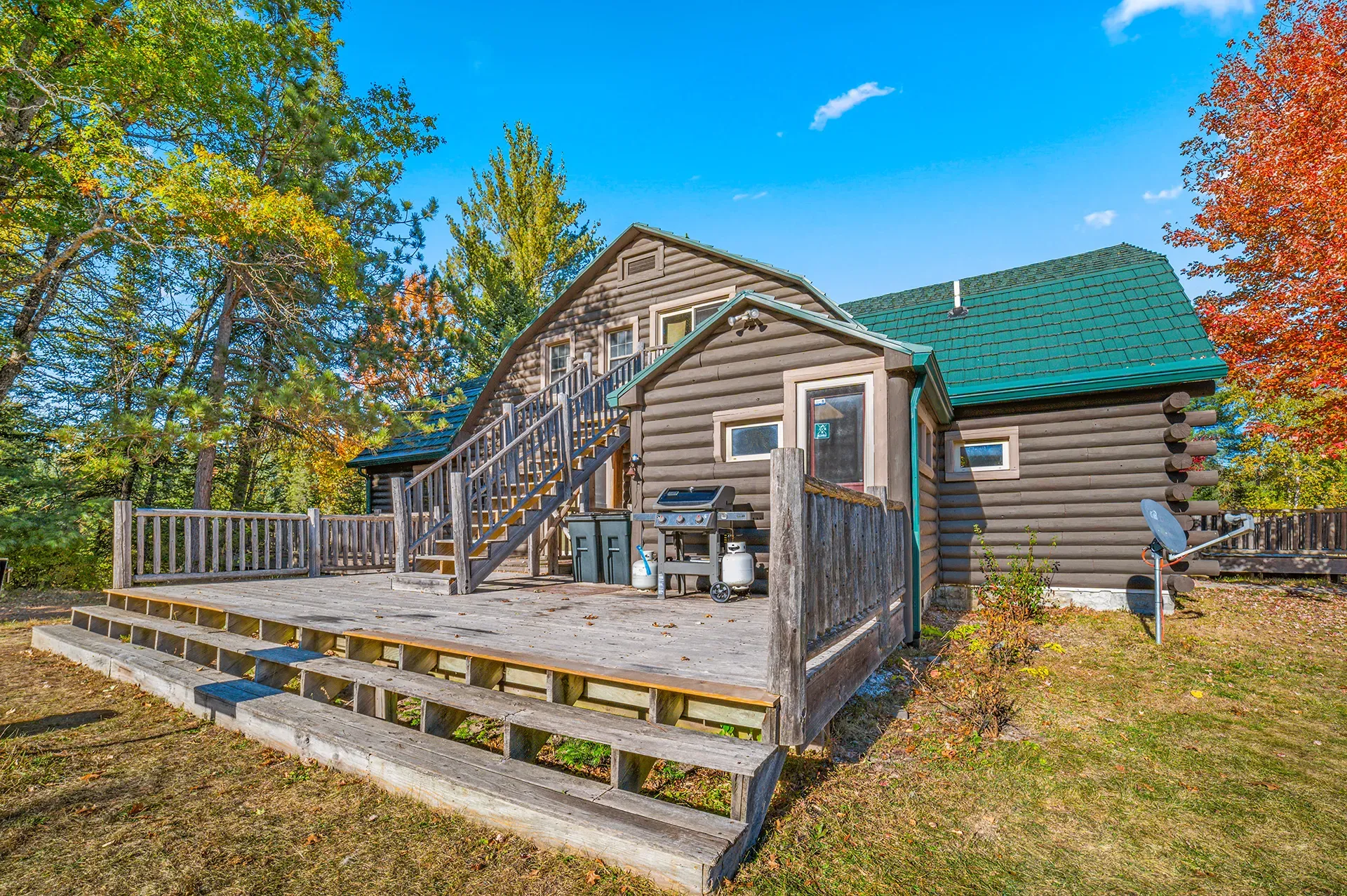 A log cabin with a large deck and stairs in front of it.