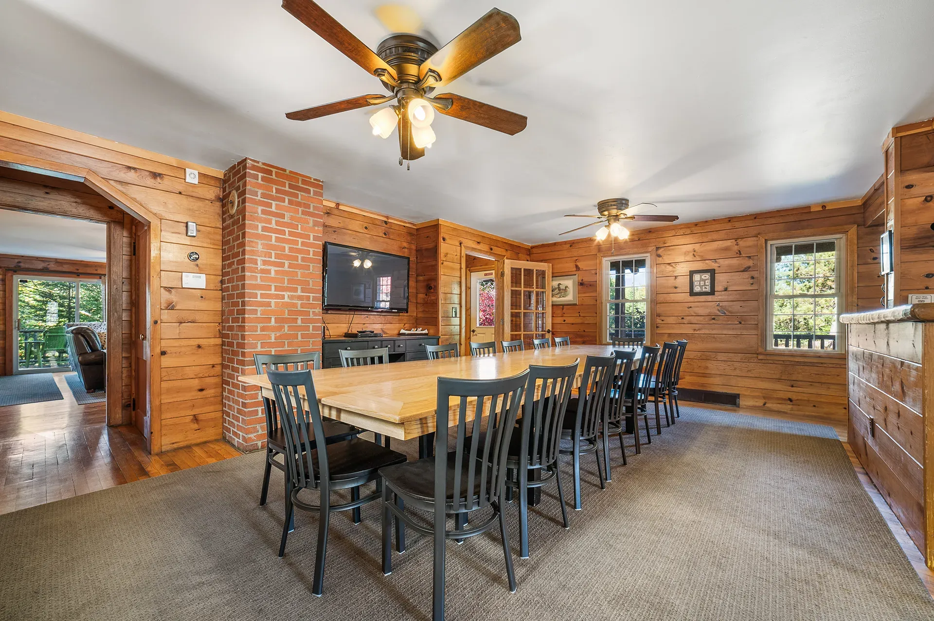 A large dining room with a long table and chairs and a ceiling fan.