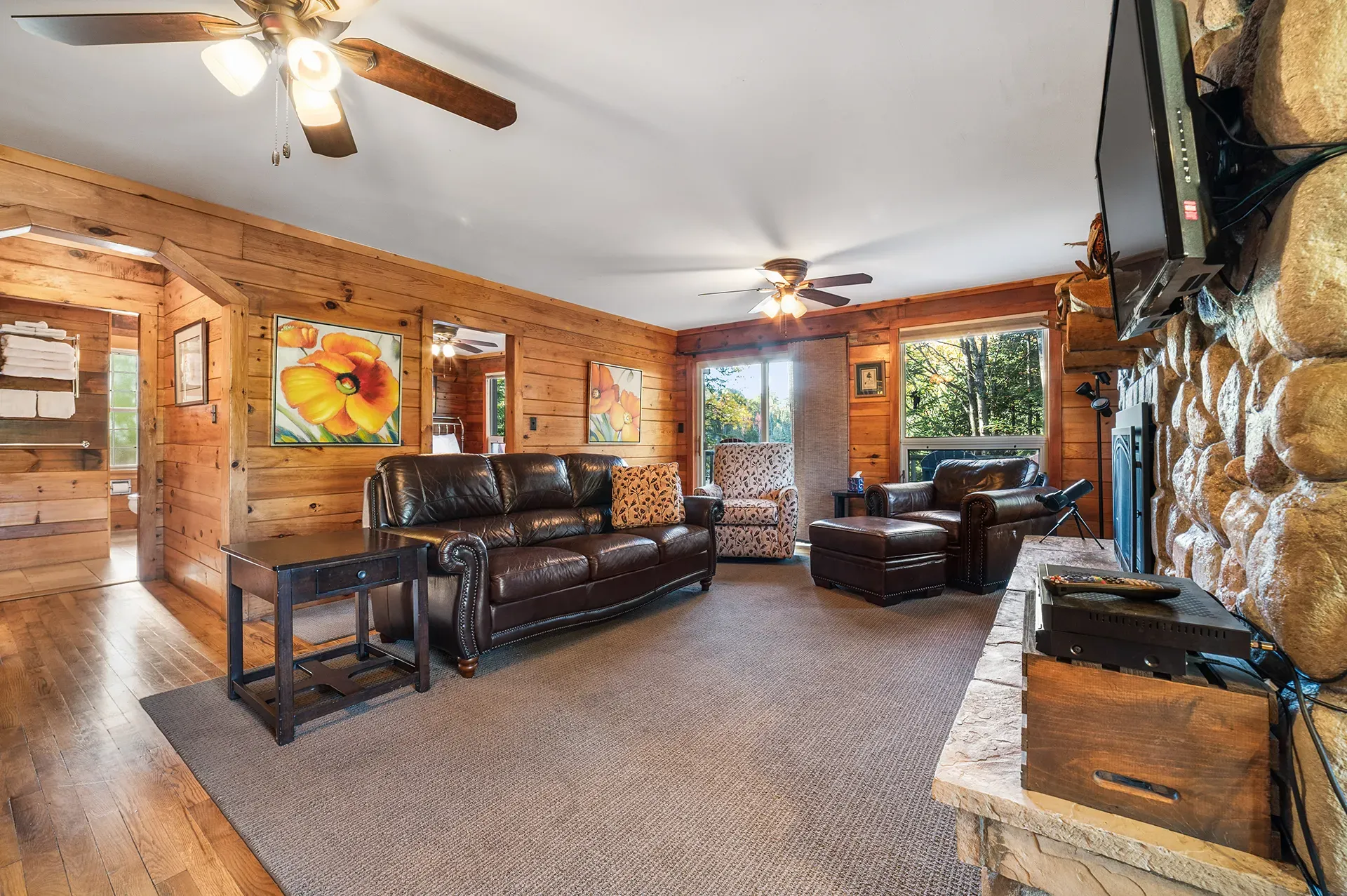 A living room in a log cabin with a couch , chairs , and a fireplace.