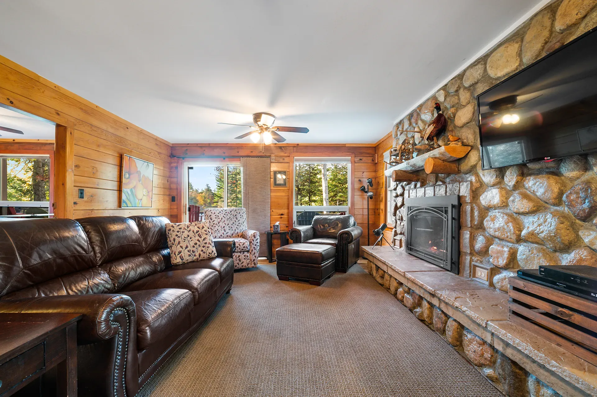A living room with a couch , chairs , fireplace and television.