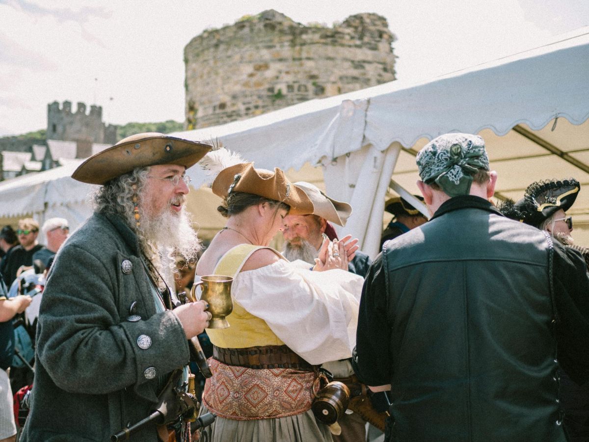 A group of people dressed in pirate costumes are standing under a tent.