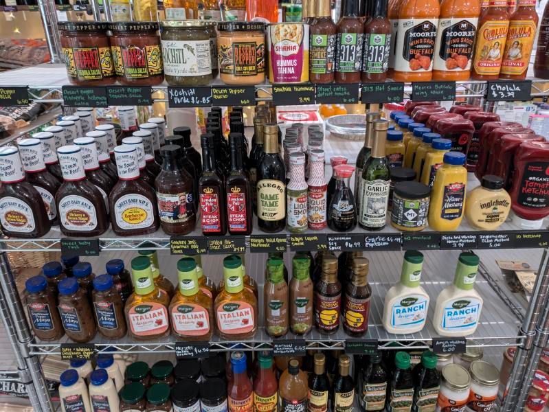 A store shelf filled with lots of condiments including ketchup and mustard