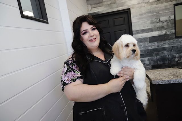 A woman is holding a small white dog in her arms.