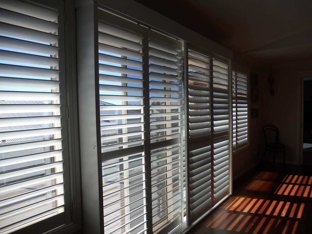A Room With A Lot Of Shutters On The Windows — Ulladulla Blinds & Home Improvements In Ulladulla, NSW