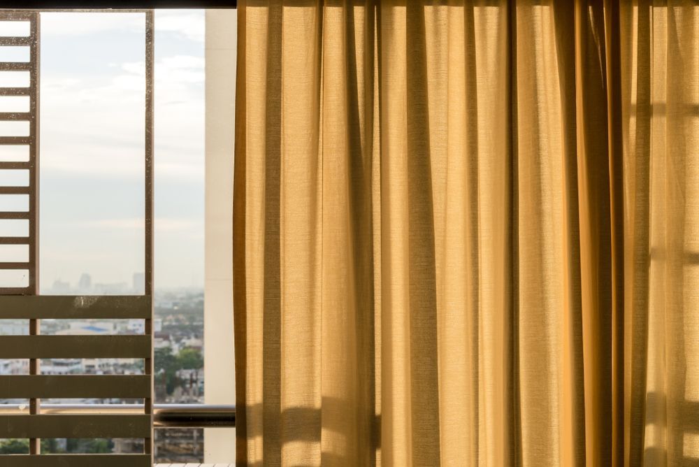 A Window With Yellow Curtains And A View Of The City — Ulladulla Blinds & Home Improvements In Ulladulla, NSW