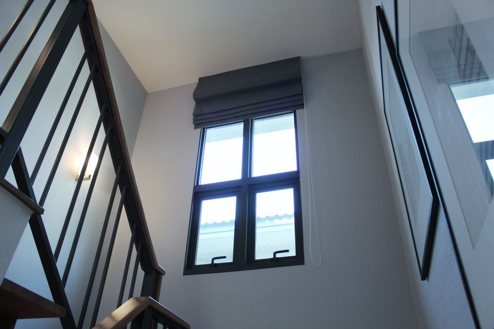 Gray Roman Shade On A Large Window Above A Staircase — Ulladulla Blinds & Home Improvements In Ulladulla, NSW