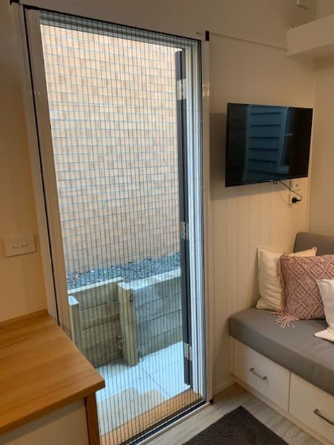 A Hinged Fly Screen Door, Open Position, Leading To A Living Room — Ulladulla Blinds & Home Improvements In Ulladulla, NSW