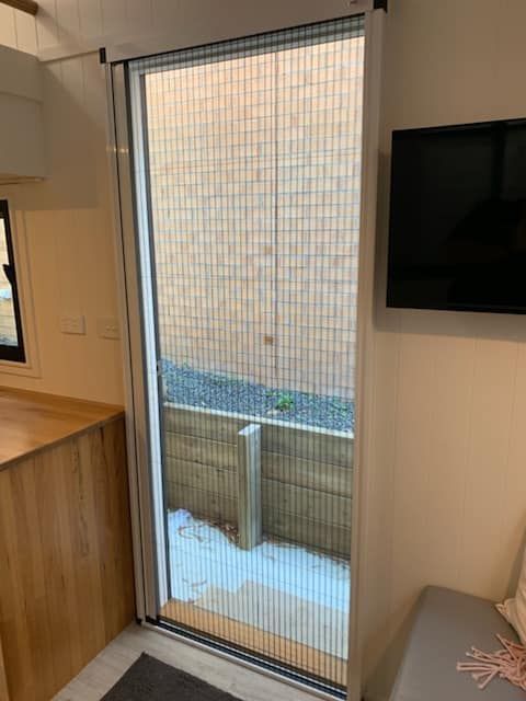 A Room With A Sliding Glass Door With A Screen On It — Ulladulla Blinds & Home Improvements In Ulladulla, NSW