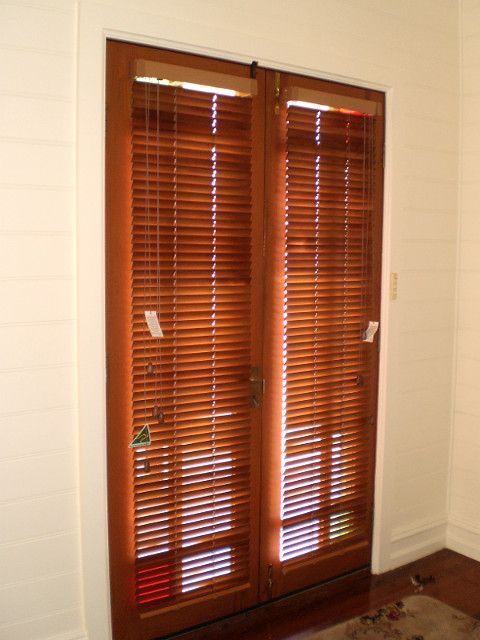 A Pair Of Wooden Blinds On A Sliding Glass Door — Ulladulla Blinds & Home Improvements In Ulladulla, NSW