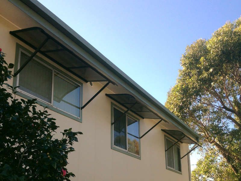 White Window Canopies Protecting A Building's Exterior — Ulladulla Blinds & Home Improvements In Ulladulla, NSW