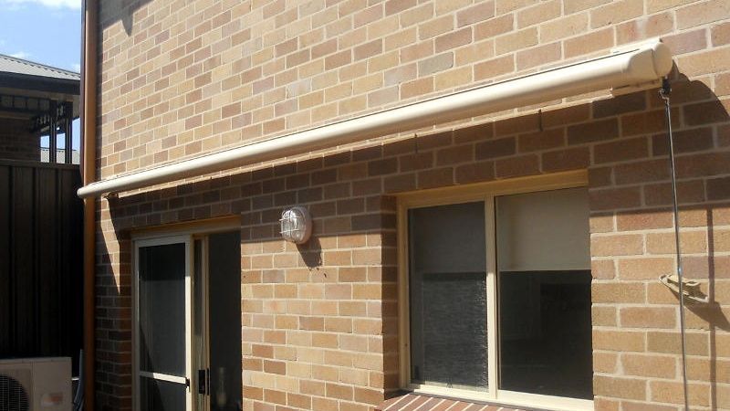 White Retractable Awning, Extended Position, Over A Brick Wall — Ulladulla Blinds & Home Improvements In Ulladulla, NSW