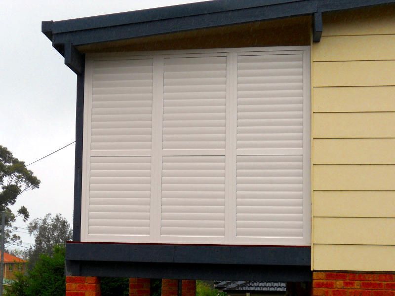 A House With White Shutters On The Side Of It — Ulladulla Blinds & Home Improvements In Ulladulla, NSW