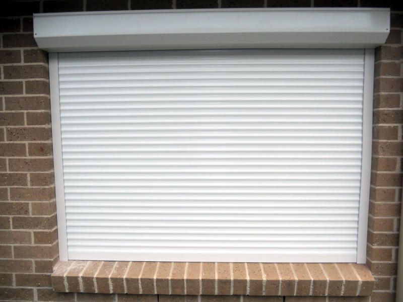 White Roller Shutter, Closed Position, On A Brick Wall — Ulladulla Blinds & Home Improvements In Ulladulla, NSW