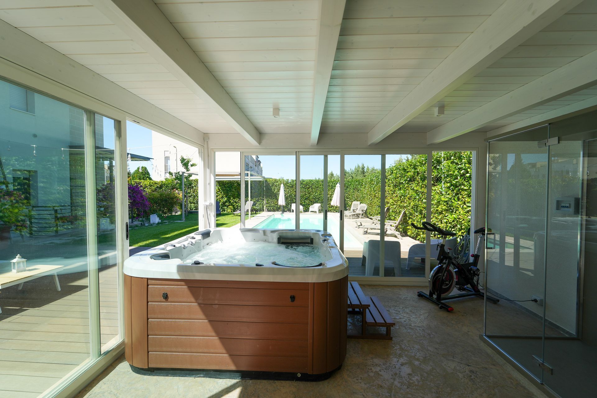 There is a Jacuzzi in the middle of a room with many windows.