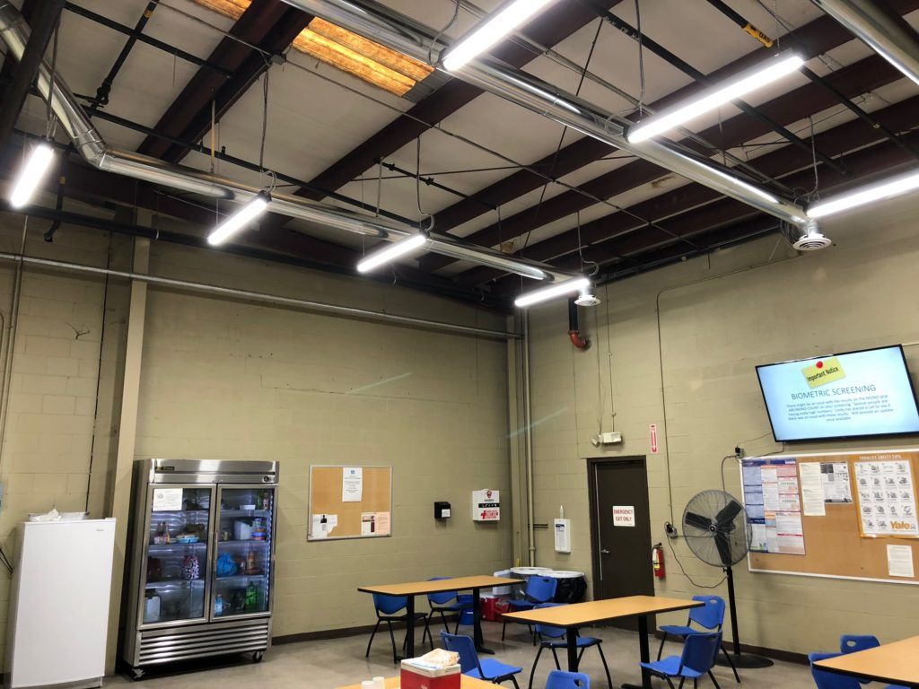 A large room with tables and chairs and a refrigerator.