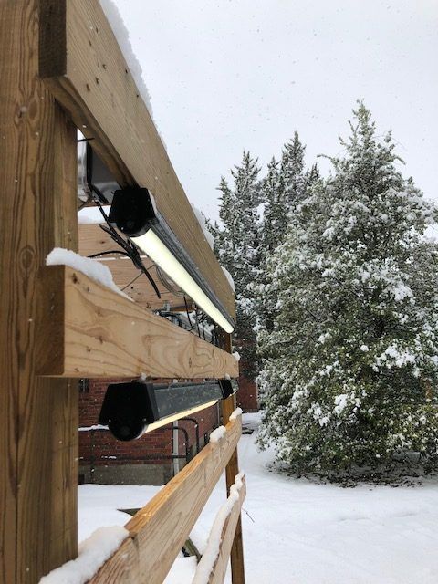 A wooden fence with snow on it and trees in the background