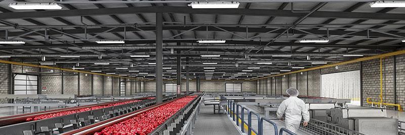 A man is walking down a conveyor belt in a large warehouse.