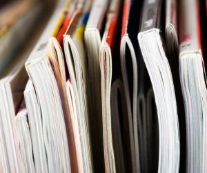 A close up of a stack of magazines on a shelf.