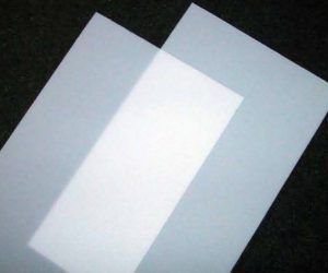 Two pieces of white paper are sitting on top of each other on a black surface.