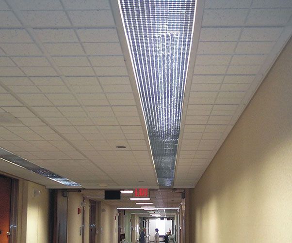 A long hallway with a red exit sign at the end