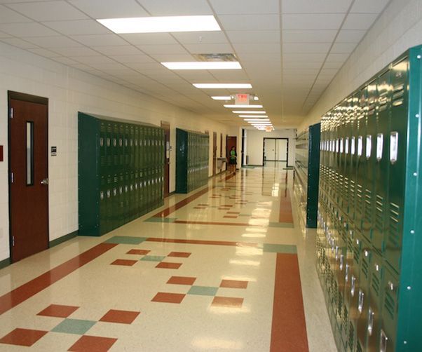 A long hallway with lots of green lockers
