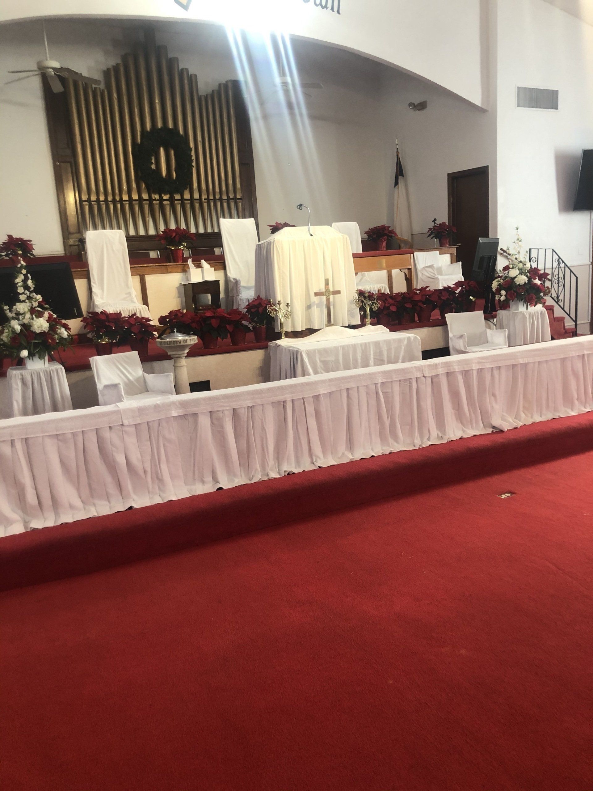 Interior of a church sanctuary with a red carpet and altar decorated for an event.