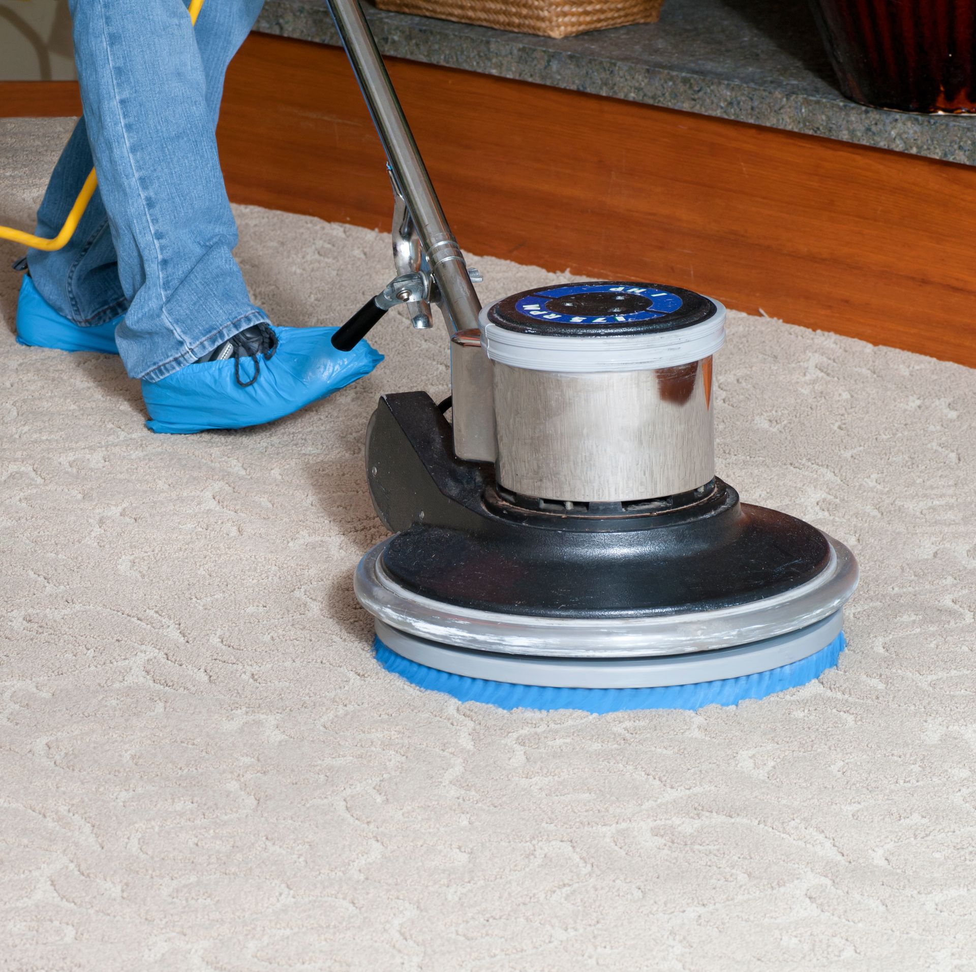 Close-up of man's legs and professional carpet scrubber, representing custodial services.