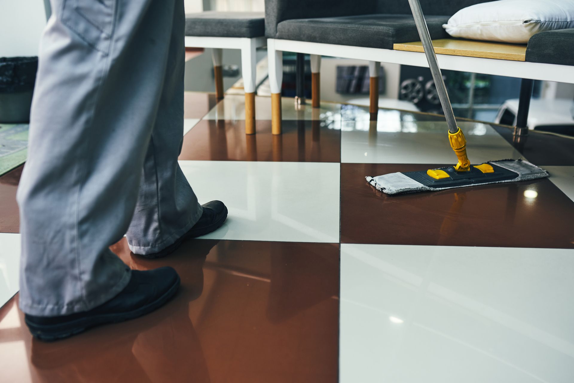 Person mopping checkered brown and white floor.