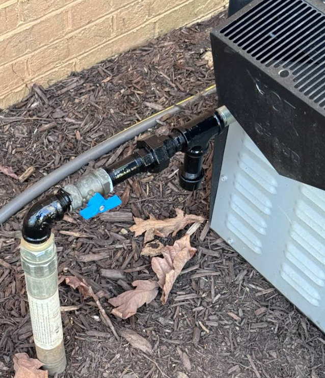 A hose is connected to a water pump next to a heater.