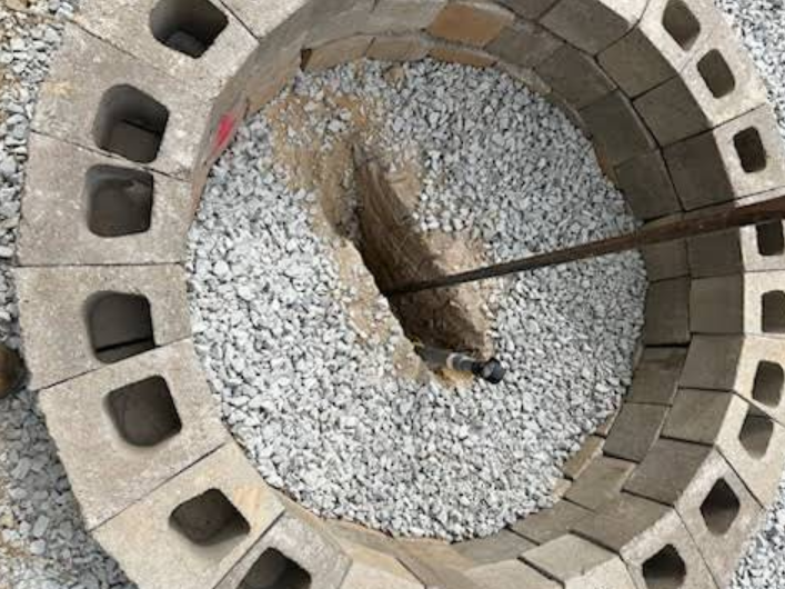 A fire pit is being built out of concrete blocks and gravel.