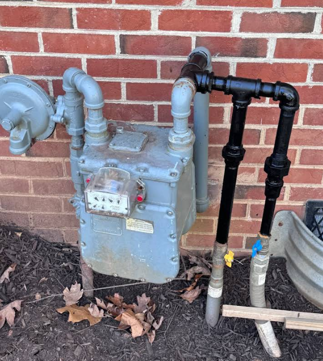 A gas meter is attached to a brick wall