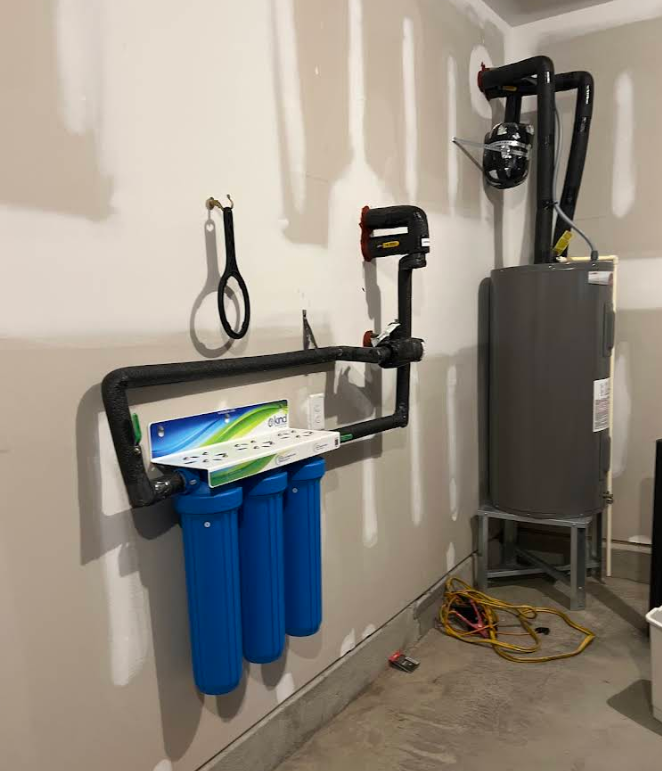 A room with a water heater and a water filter on the wall