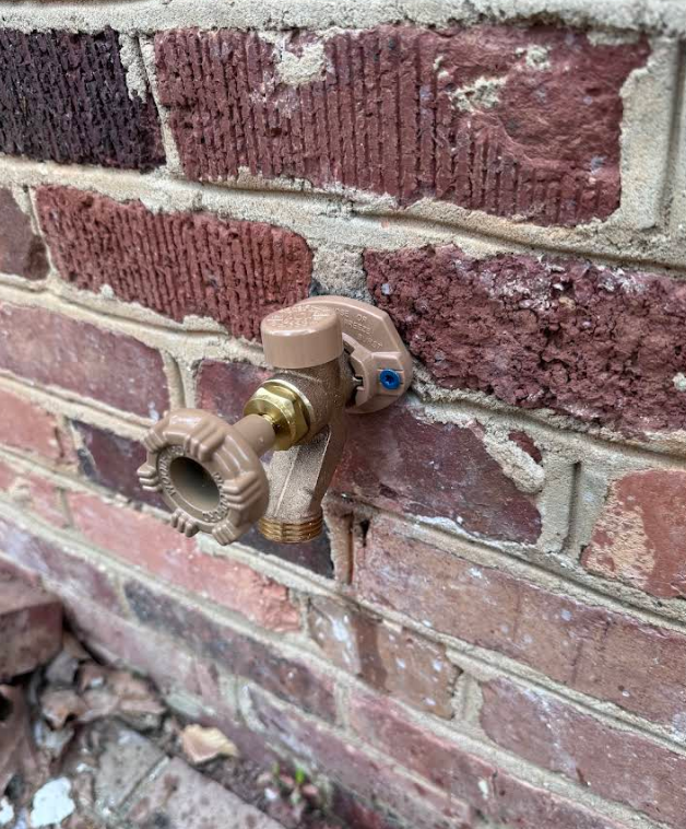 A close up of a faucet on a brick wall.